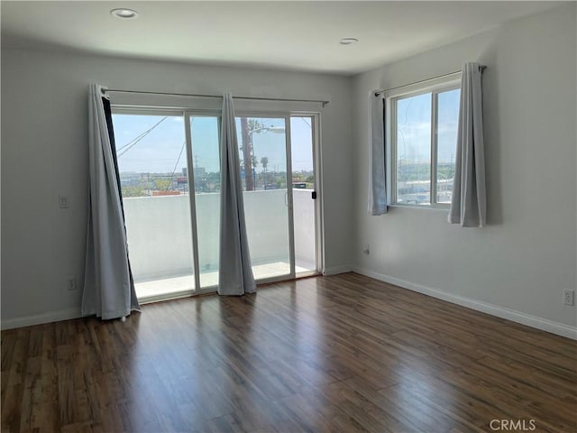 empty room featuring dark wood-style flooring, baseboards, and recessed lighting