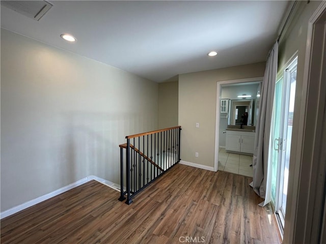 hall with an upstairs landing, wood finished floors, baseboards, and recessed lighting