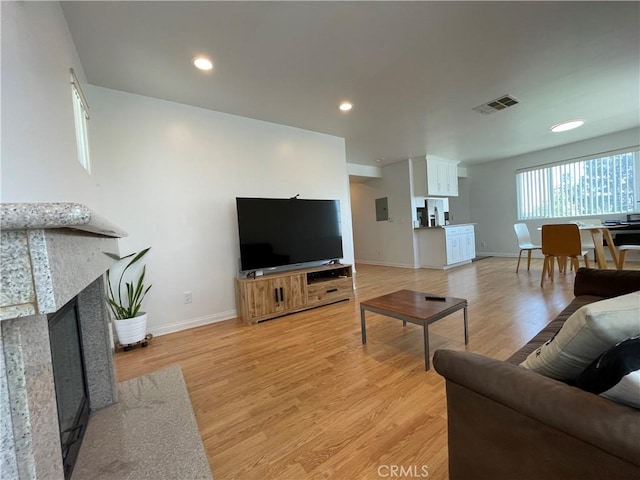 living room with baseboards, a tiled fireplace, light wood-type flooring, and recessed lighting