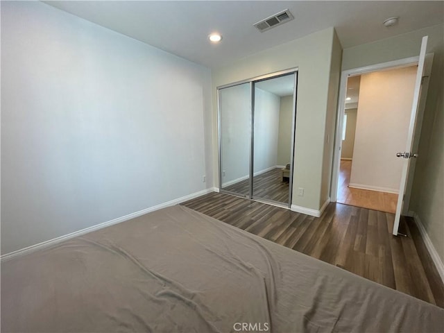 unfurnished bedroom with wood finished floors, baseboards, a closet, and recessed lighting