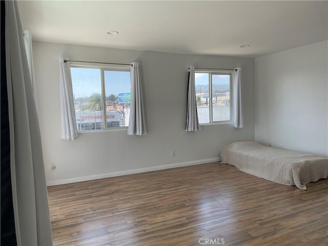 bedroom featuring wood finished floors, multiple windows, baseboards, and recessed lighting