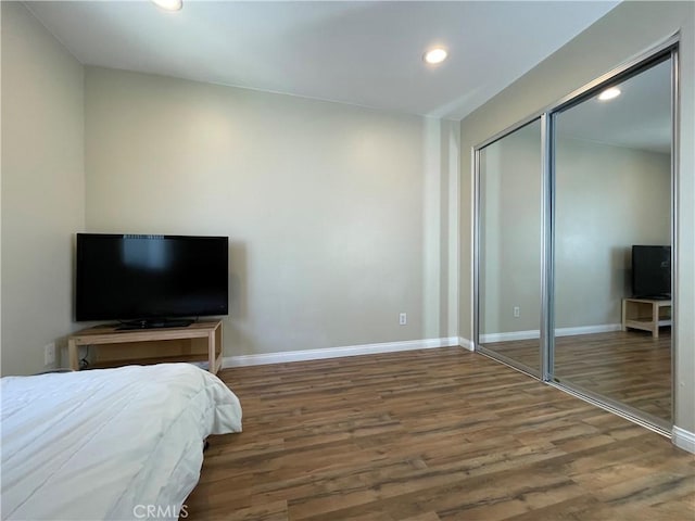 bedroom featuring wood finished floors, recessed lighting, baseboards, and a closet