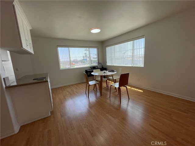 dining space featuring light wood-style floors and baseboards