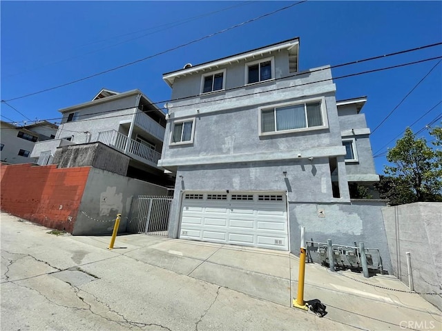view of front facade with a garage, fence, stucco siding, and concrete driveway