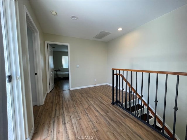 hall featuring an upstairs landing, wood finished floors, baseboards, and recessed lighting