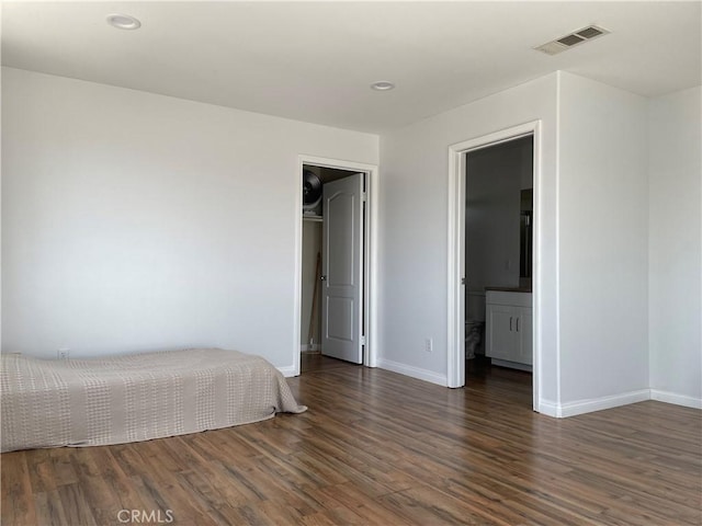bedroom featuring wood finished floors, baseboards, recessed lighting, and a walk in closet