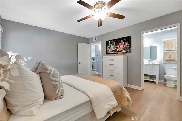 bedroom with light wood-style floors, ensuite bath, baseboards, and ceiling fan