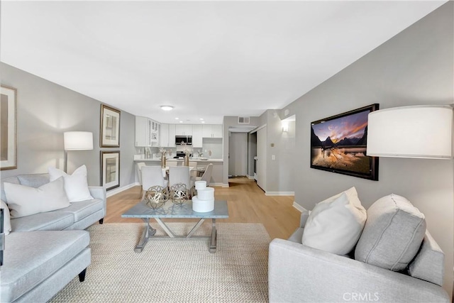 living area with wine cooler, light wood finished floors, baseboards, and recessed lighting