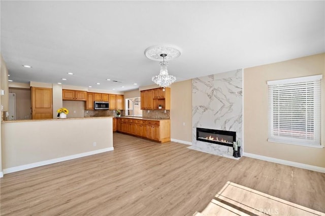 unfurnished living room featuring plenty of natural light, a chandelier, light wood-style flooring, recessed lighting, and a premium fireplace