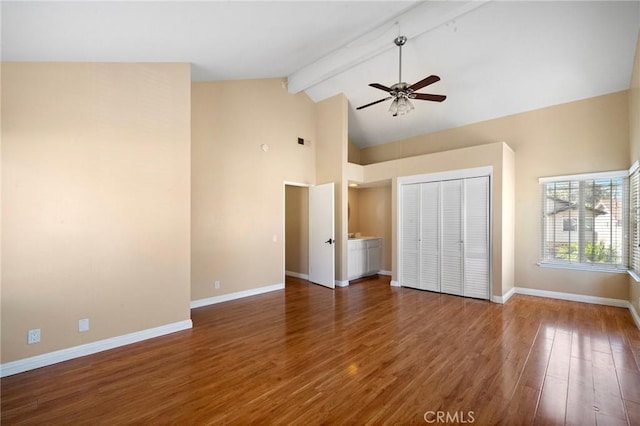 unfurnished bedroom with beamed ceiling, high vaulted ceiling, wood finished floors, baseboards, and a closet