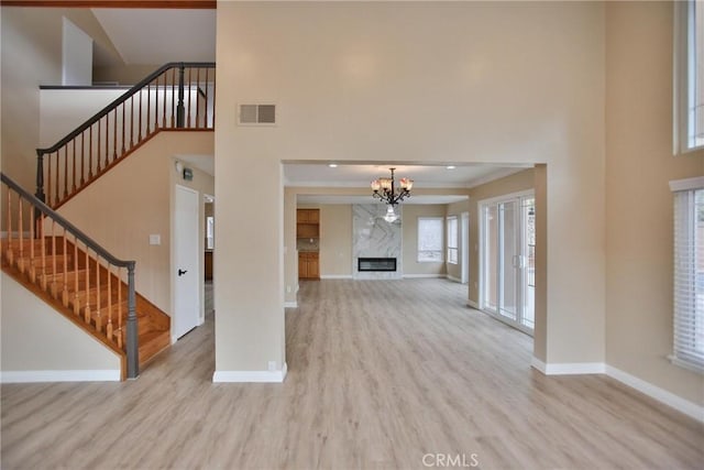 unfurnished living room with wood finished floors, baseboards, a high ceiling, and stairway