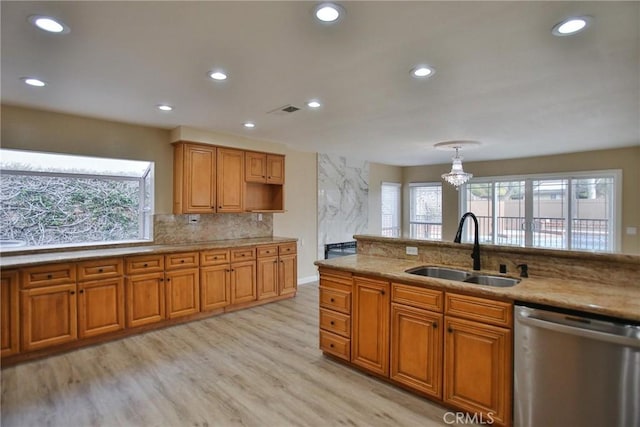 kitchen with a sink, stainless steel dishwasher, plenty of natural light, brown cabinetry, and recessed lighting