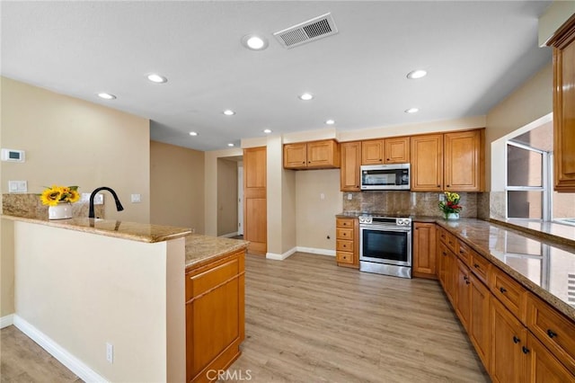kitchen featuring appliances with stainless steel finishes, light stone countertops, recessed lighting, baseboards, and light wood-style flooring