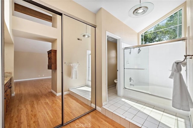 full bathroom with wood finished floors, toilet, vaulted ceiling, vanity, and combined bath / shower with glass door