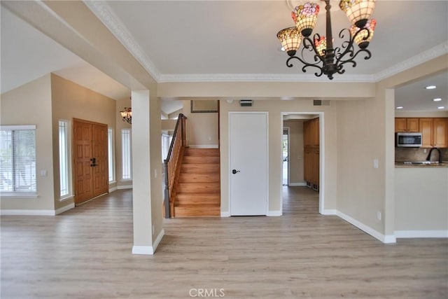 entryway with a chandelier, stairs, light wood finished floors, baseboards, and crown molding