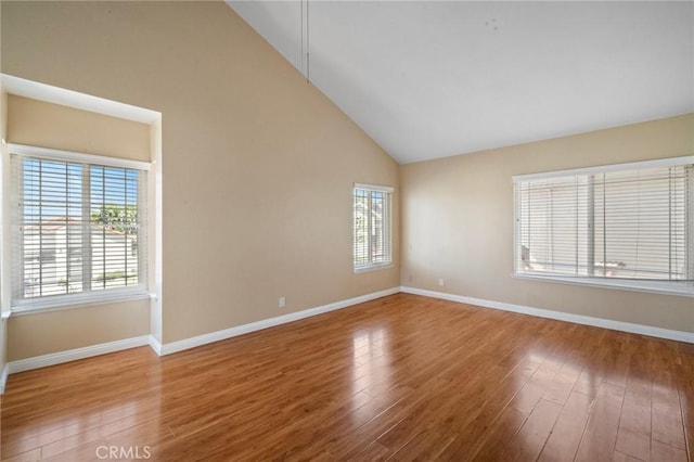 unfurnished room with high vaulted ceiling, wood finished floors, and baseboards