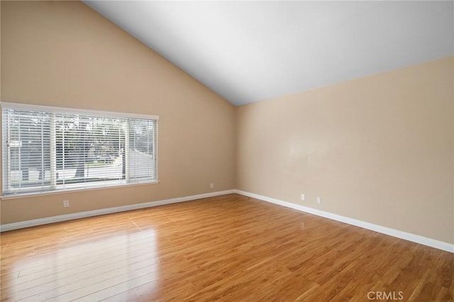 spare room with light wood-style floors, lofted ceiling, and baseboards