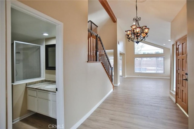 foyer featuring wood finished floors, stairway, a chandelier, baseboards, and high vaulted ceiling