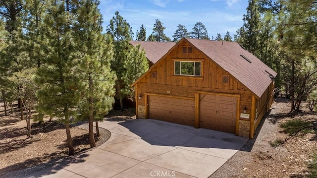 1020 Heritage Trl, Big Bear City, CA 92314 - view of front facade featuring roof with shingles, a garage, and stone siding