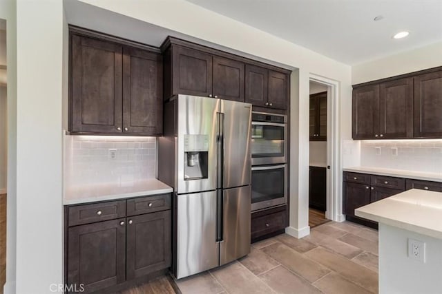 kitchen featuring appliances with stainless steel finishes, dark brown cabinets, light countertops, backsplash, and recessed lighting