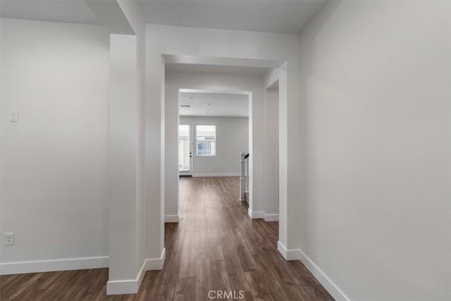 hallway featuring dark wood finished floors, baseboards, and an upstairs landing