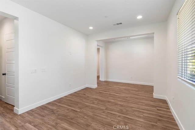 empty room featuring wood finished floors, recessed lighting, and baseboards