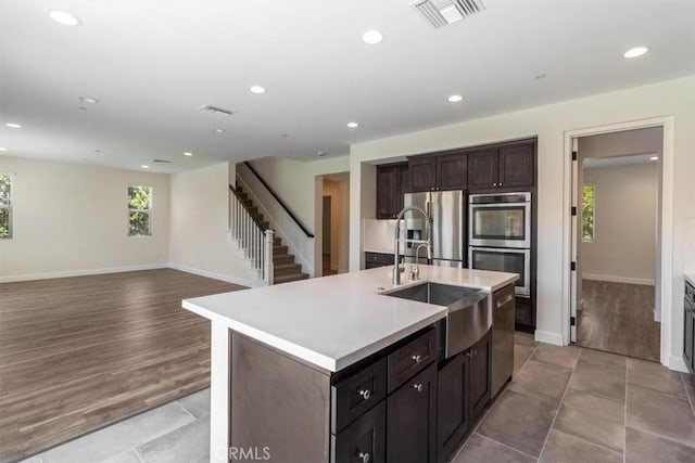 kitchen featuring stainless steel appliances, a sink, light countertops, recessed lighting, and baseboards