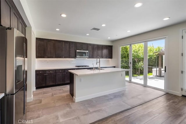 kitchen featuring stainless steel appliances, a sink, light countertops, dark brown cabinetry, and recessed lighting