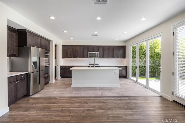 kitchen with appliances with stainless steel finishes, dark brown cabinets, light countertops, recessed lighting, and light wood-style flooring