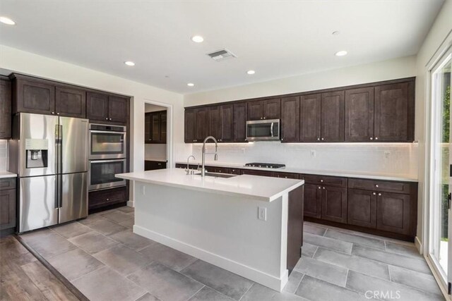 kitchen with stainless steel appliances, a sink, dark brown cabinetry, light countertops, and recessed lighting