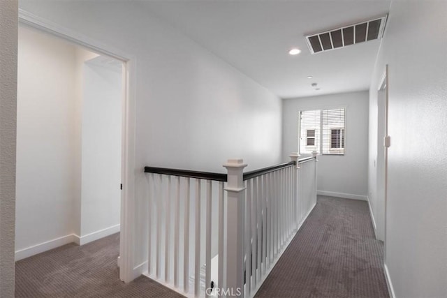 corridor with carpet flooring, an upstairs landing, baseboards, and recessed lighting