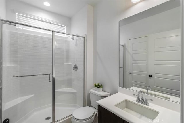 bathroom featuring a shower stall, toilet, and vanity