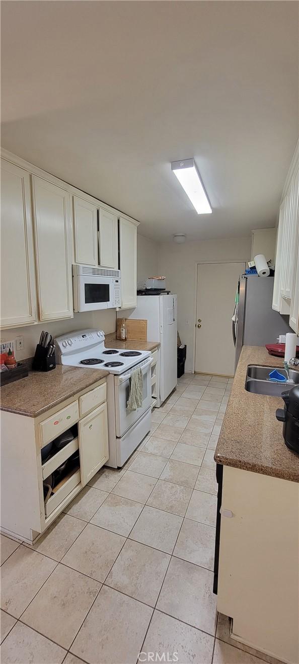 5400 Lindley Ave Unit 116, Encino, CA 91316 - kitchen with white appliances, light tile patterned flooring, white cabinets, and a sink
