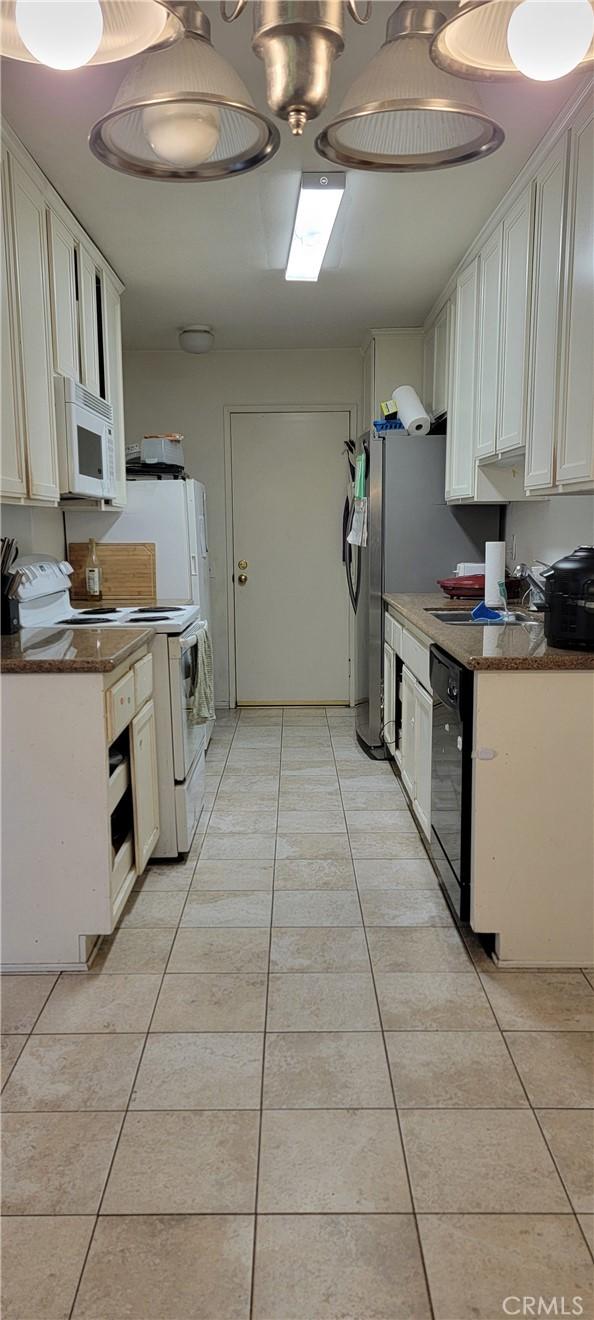 5400 Lindley Ave Unit 116, Encino, CA 91316 - kitchen with white appliances, light tile patterned floors, white cabinets, and dark stone countertops