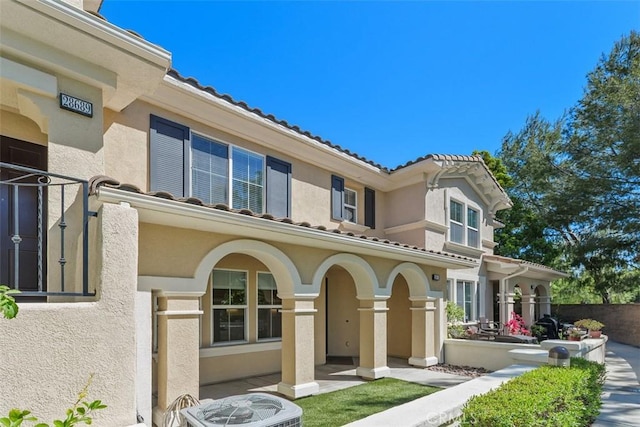 view of front of home featuring stucco siding, a tiled roof, and central AC