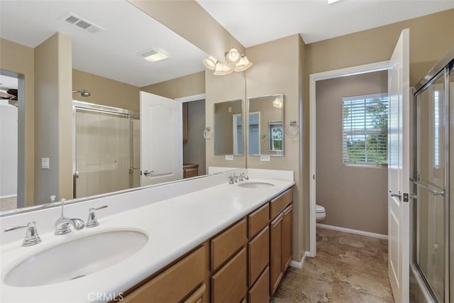 bathroom featuring toilet, a stall shower, double vanity, and baseboards