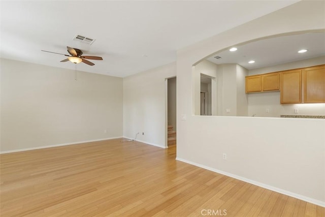 unfurnished living room featuring ceiling fan, light wood-type flooring, recessed lighting, baseboards, and arched walkways