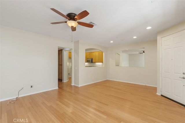 unfurnished living room featuring ceiling fan, recessed lighting, light wood-type flooring, baseboards, and arched walkways