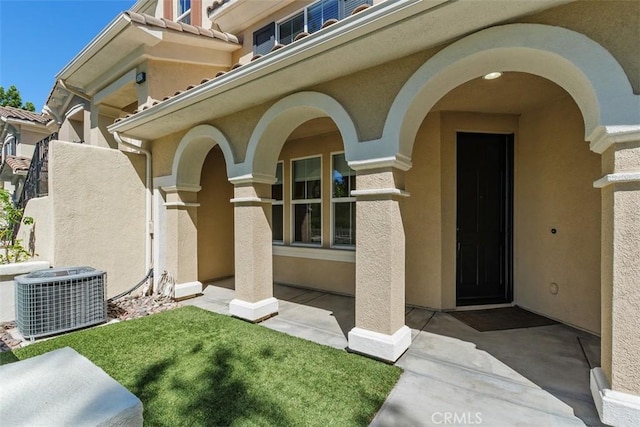view of exterior entry with cooling unit and stucco siding