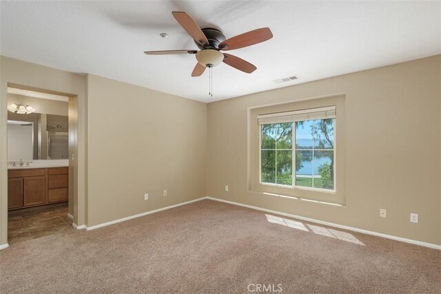 unfurnished bedroom with carpet floors, baseboards, ensuite bath, and ceiling fan