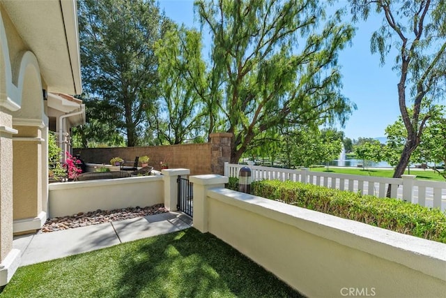 view of patio / terrace with a fenced front yard, a water view, and a gate