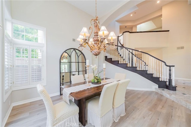 dining room featuring high vaulted ceiling, a chandelier, light wood-style floors, stairway, and baseboards