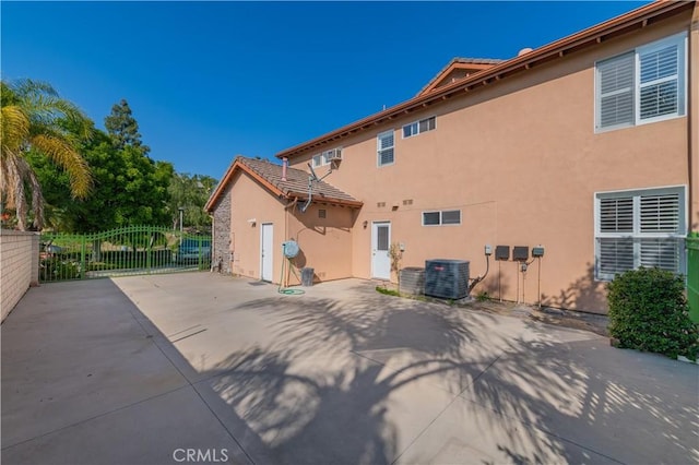 rear view of property featuring stucco siding, central AC, fence, and a patio