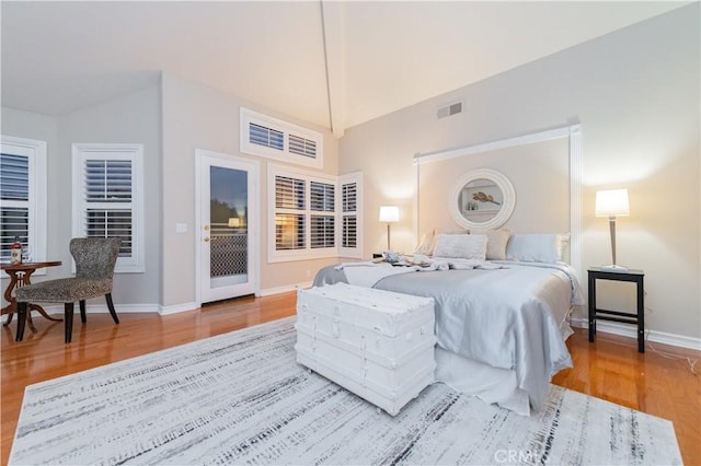 bedroom with wood finished floors, baseboards, access to outside, and vaulted ceiling