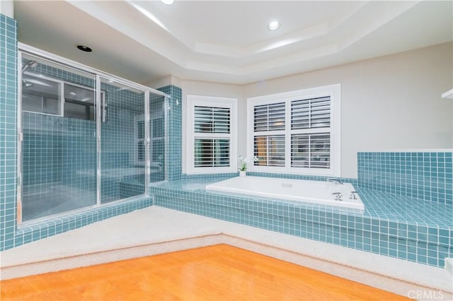 bathroom with a garden tub, a shower stall, a raised ceiling, and recessed lighting