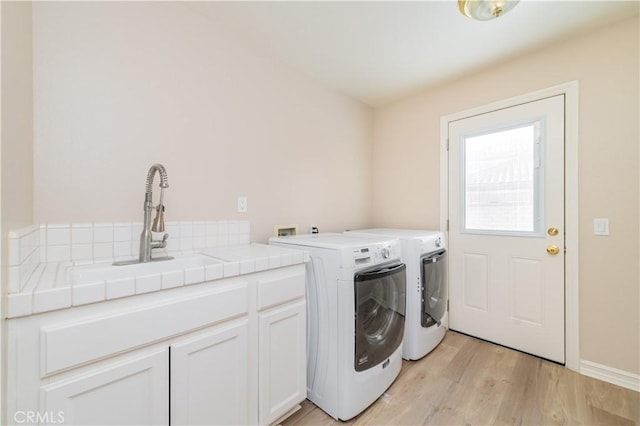 laundry area featuring washing machine and clothes dryer, cabinet space, and light wood-type flooring