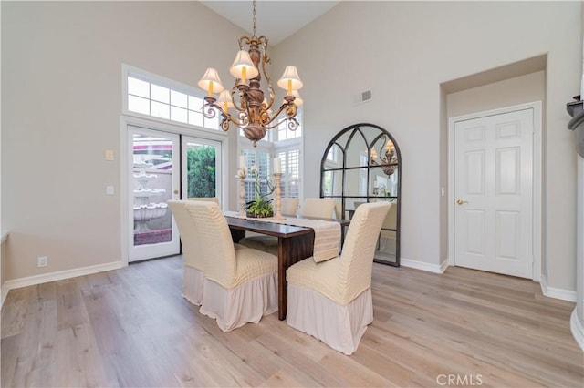 dining area with a chandelier, high vaulted ceiling, light wood finished floors, and baseboards