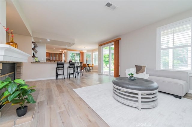 living area with light wood-style floors, a brick fireplace, recessed lighting, and baseboards