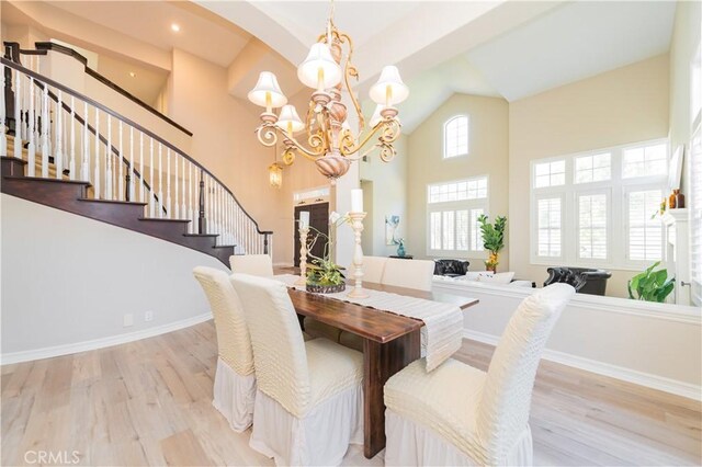dining room with wood finished floors, stairs, a chandelier, high vaulted ceiling, and baseboards