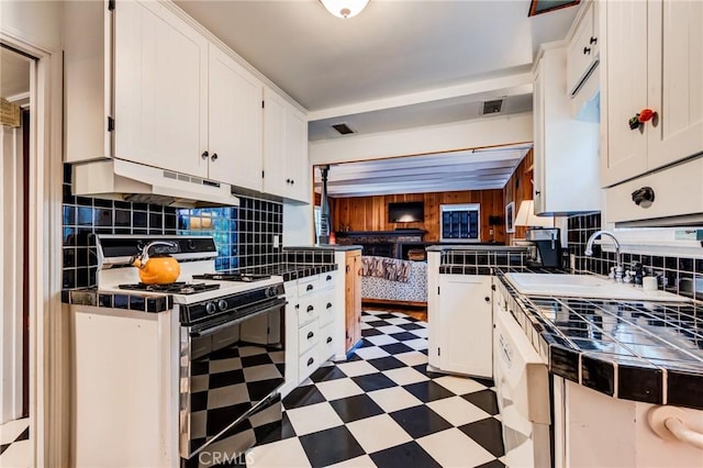 222 Holiday Dr, Lake Arrowhead, CA 92352 - kitchen featuring range with gas stovetop, under cabinet range hood, light flooring, tile countertops, and white cabinets